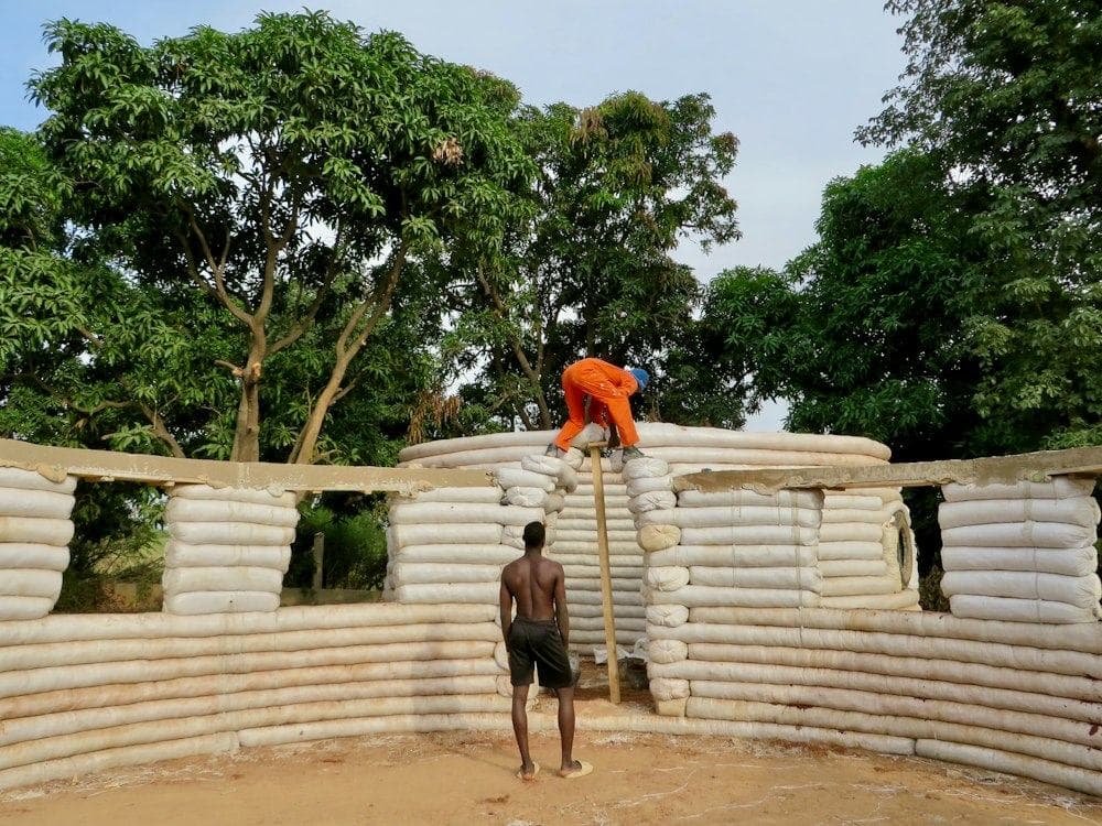 A man standing on a pile of bricks at an earth-building site